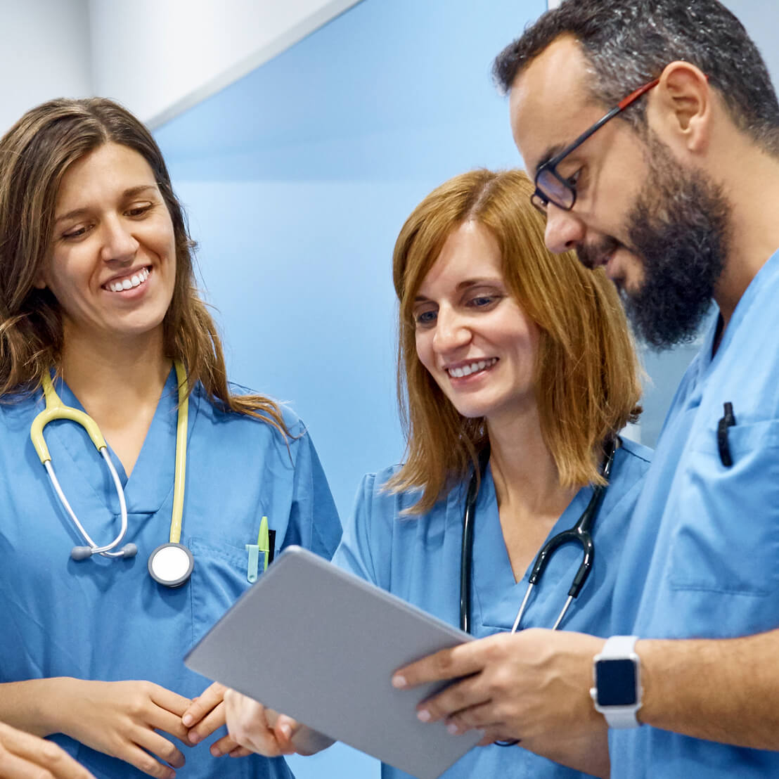 Three nurses viewing health data on a tablet