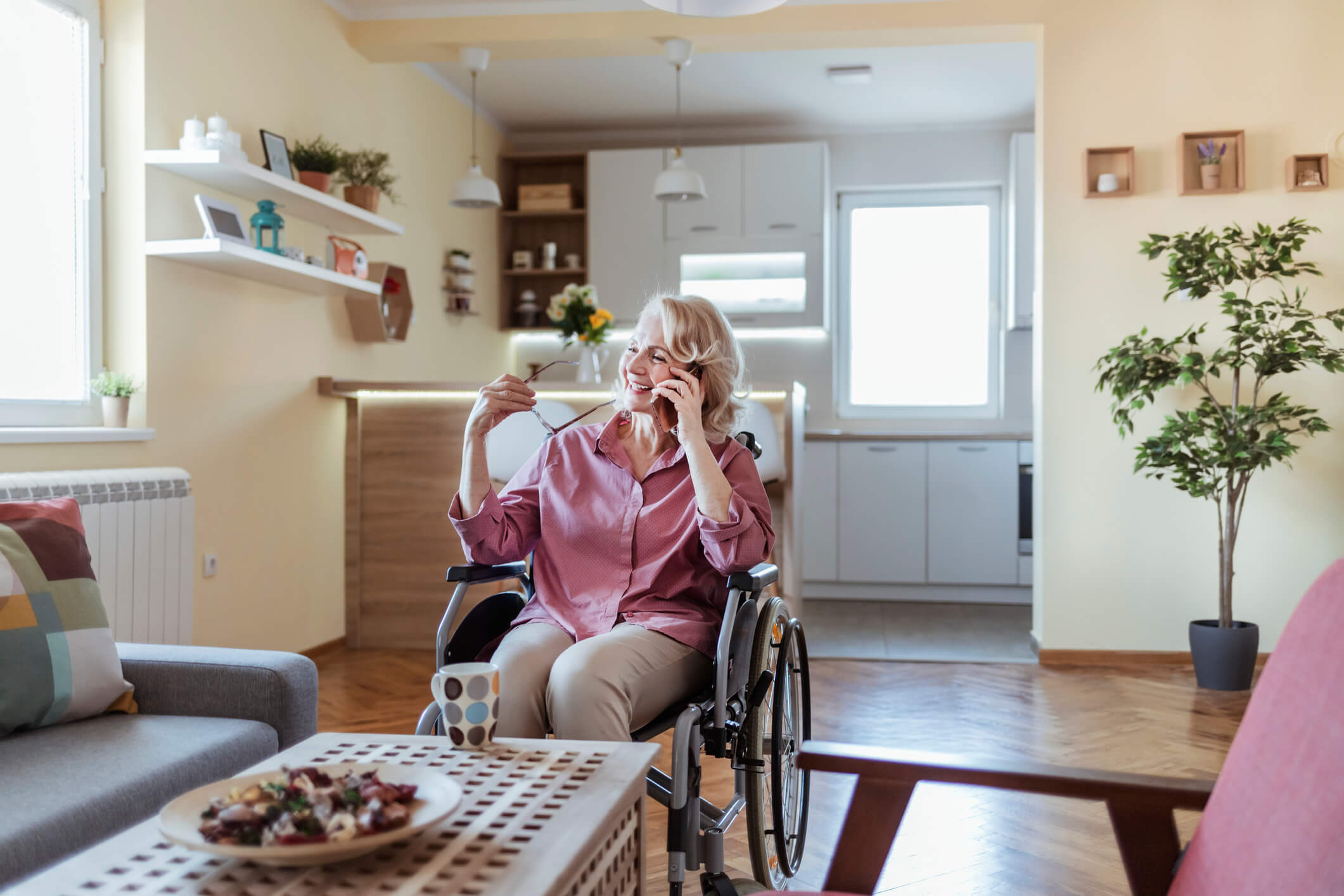 A woman smiling while talking on her cellphone and in a wheelchair