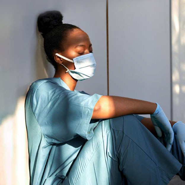A nurse sitting down wearing a medica face mask